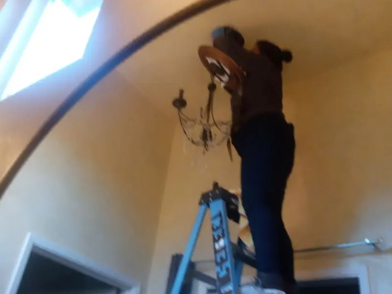 Electrician installing a chandelier in a Dormont residence